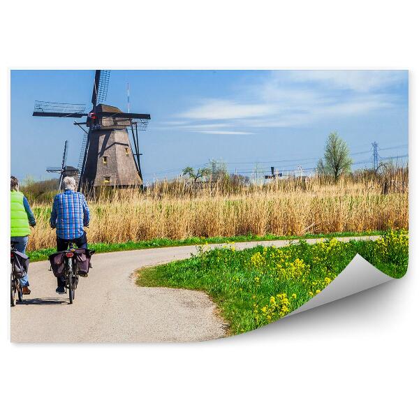 Fotótapéta Férfi kerékpárosok egy szélmalomra néző úton