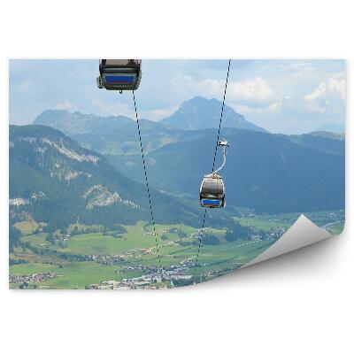 Öntapadó fotótapéta Sífelvonó hegyek Alpok Ausztria házak tűlevelű fák ég felhők