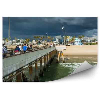 Öntapadó fotótapéta Pier beach óceán felhőkarcolók pálmafák emberek sötét felhők